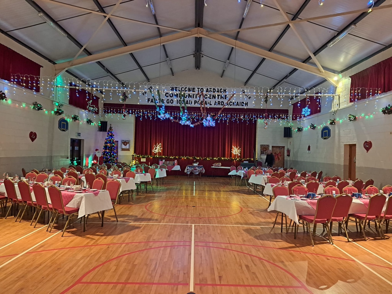 The Main Hall set for a Christmas dinner, stage curtains and welcome banner behind