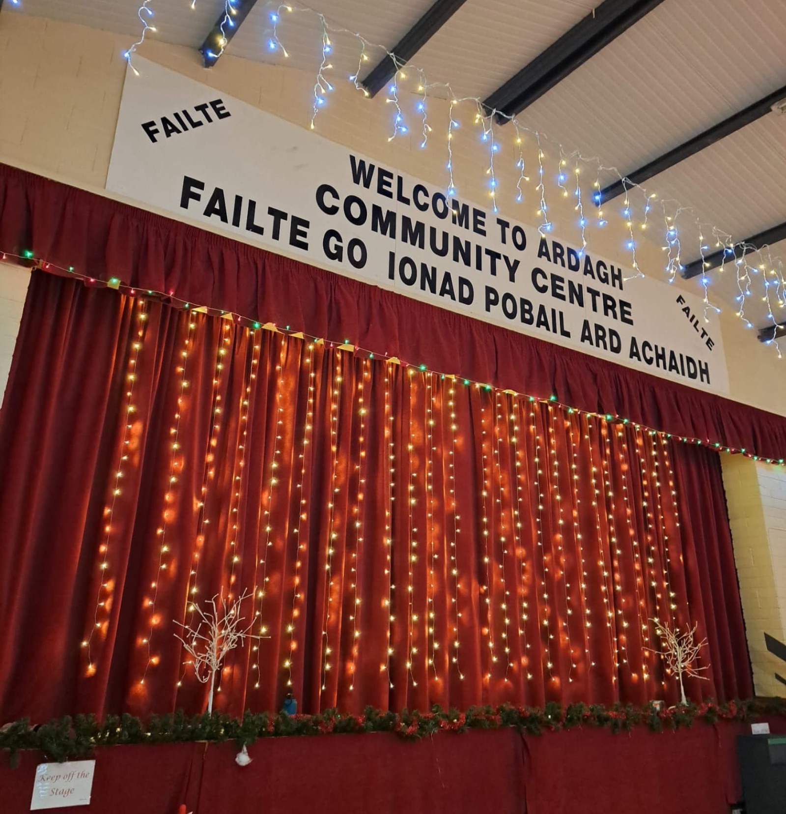 The stage curtains and the welcome banner: Fáilte go Ionad Pobail Ard Achaidh